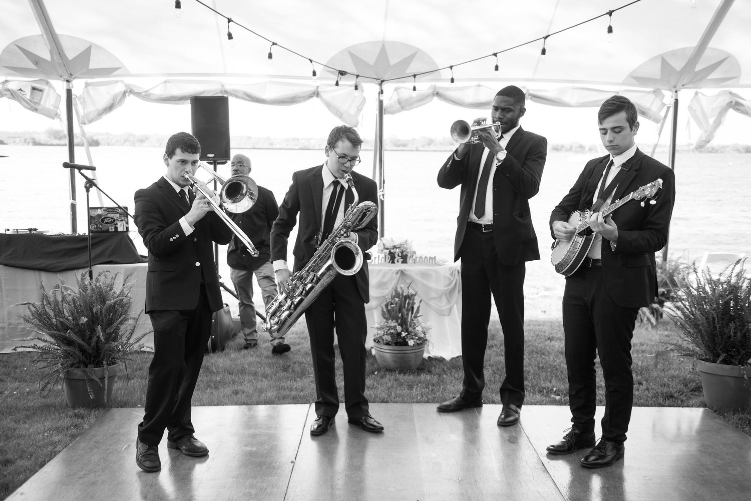 Brass band with trombone, baritone sax, trumpet and banjo under a wedding tent