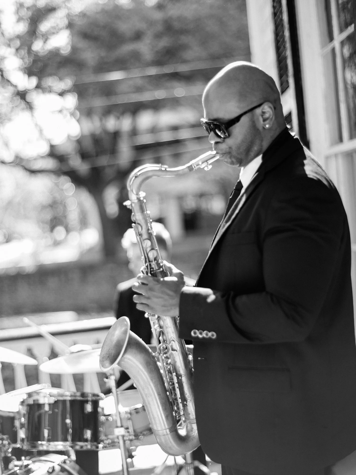 Saxophonist in sunglasses with drum kit behind